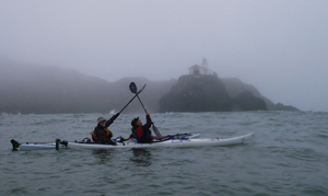 McHugh and Barnes give a paddle salute to the Point Bonita light. Photo by John Weed.